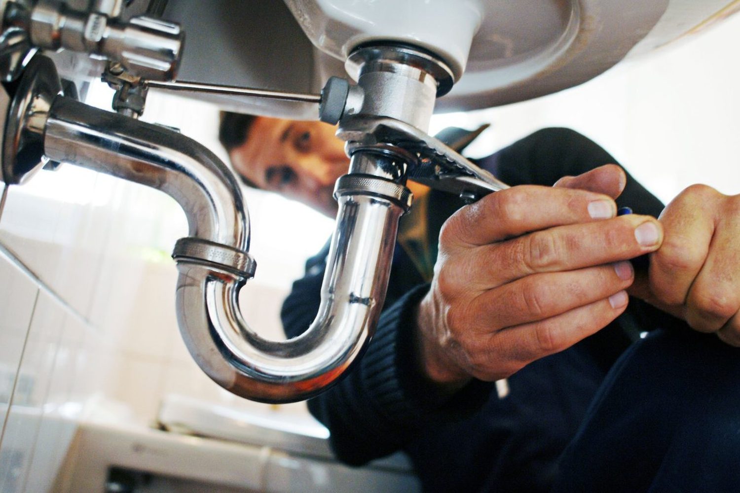 Plumber working on a fixture with a wrench